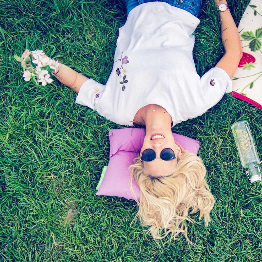 Glückliche Frau auf Wiese mit mySheepi COMPACT Kissen