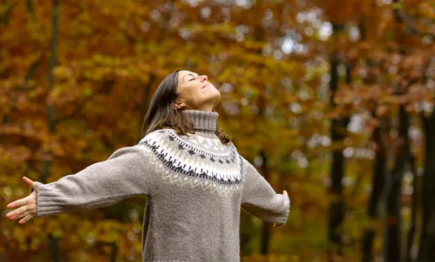 Frau atmet in Herbstwald, Sinnbild für Hypoallergen